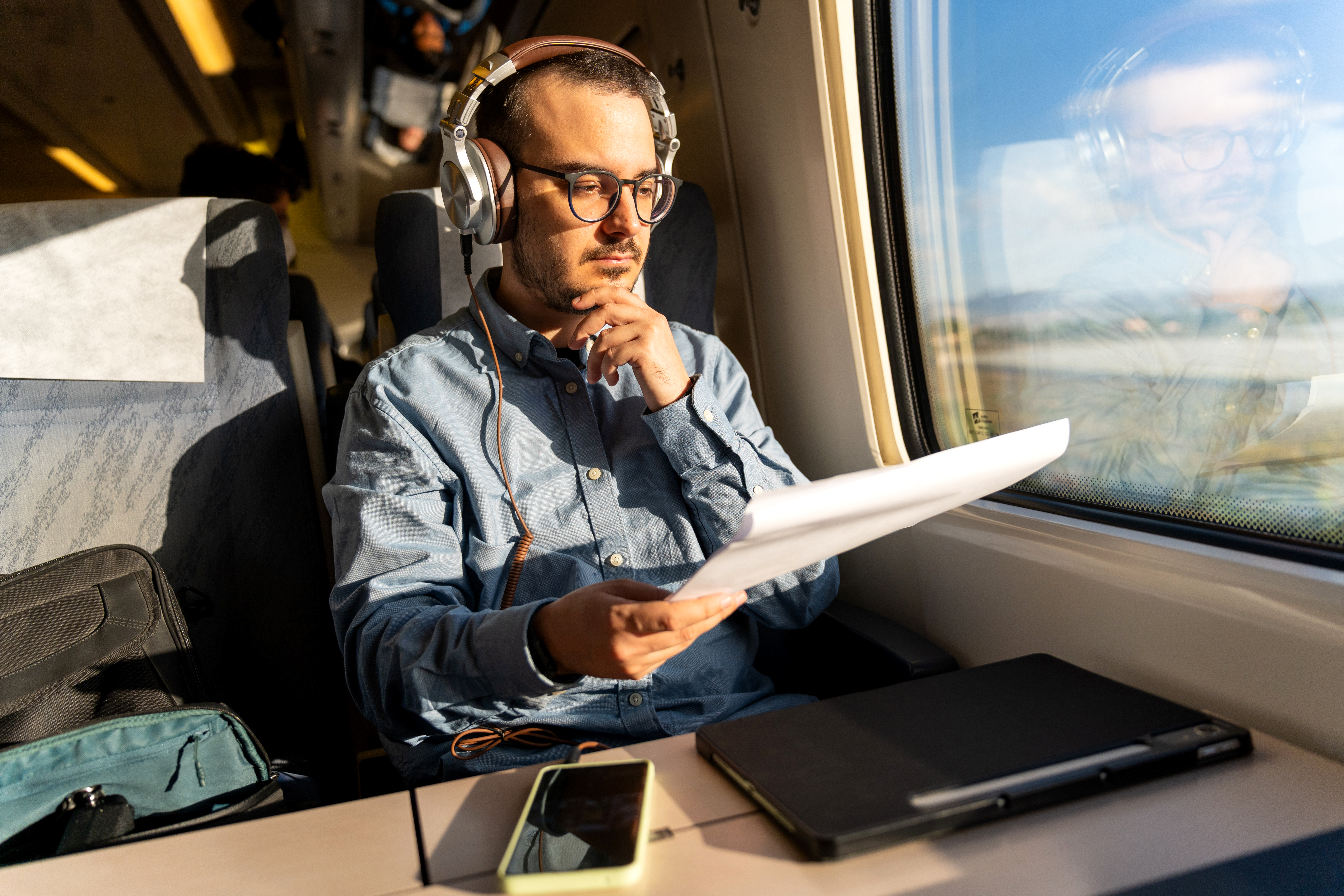 man-wearing-headphones-reading-document-on-train-j-2026-01-11-10-49-43-utc
