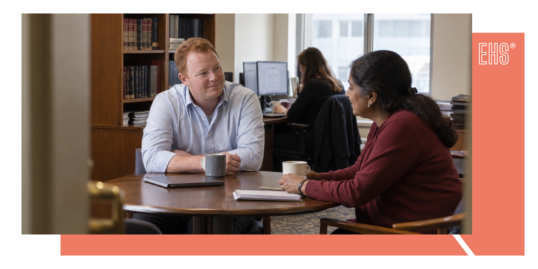Colleagues discussing work in a shared office with EHS branding